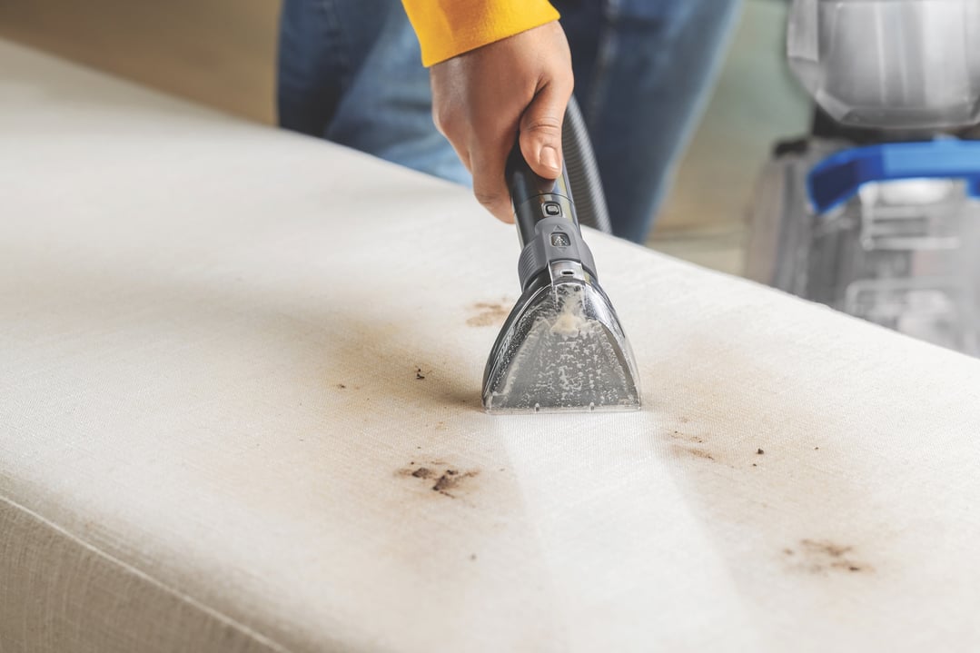 Hand using a carpet and upholstery cleaner to clean a dirty mattress