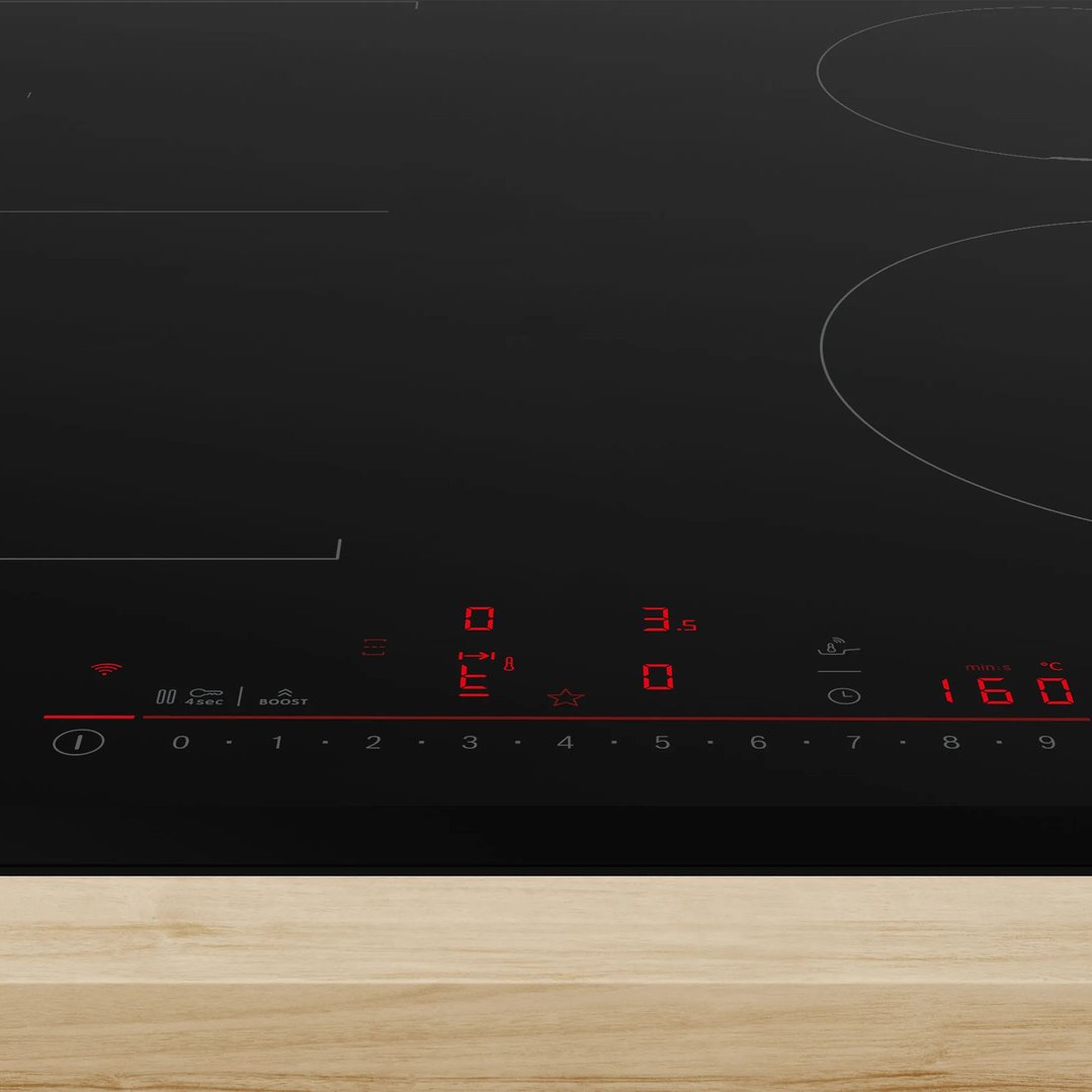 Black induction cooktop with red digital display on a light wooden countertop