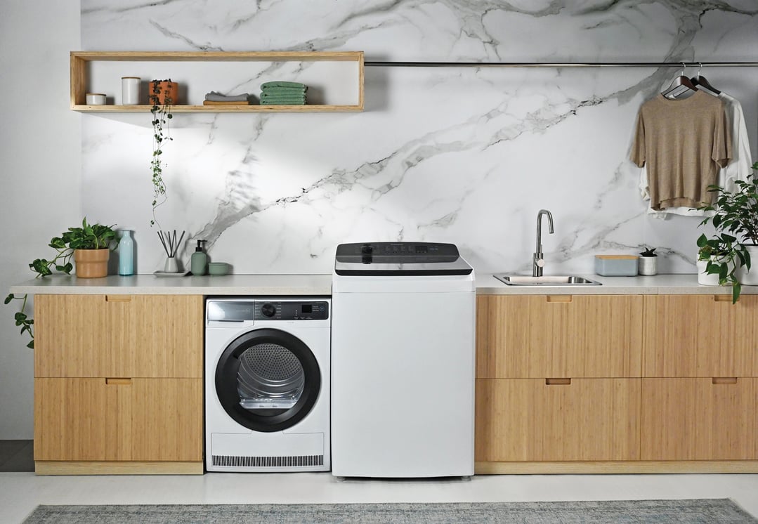 A white heat pump dryer and washing machine in a modern laundry room