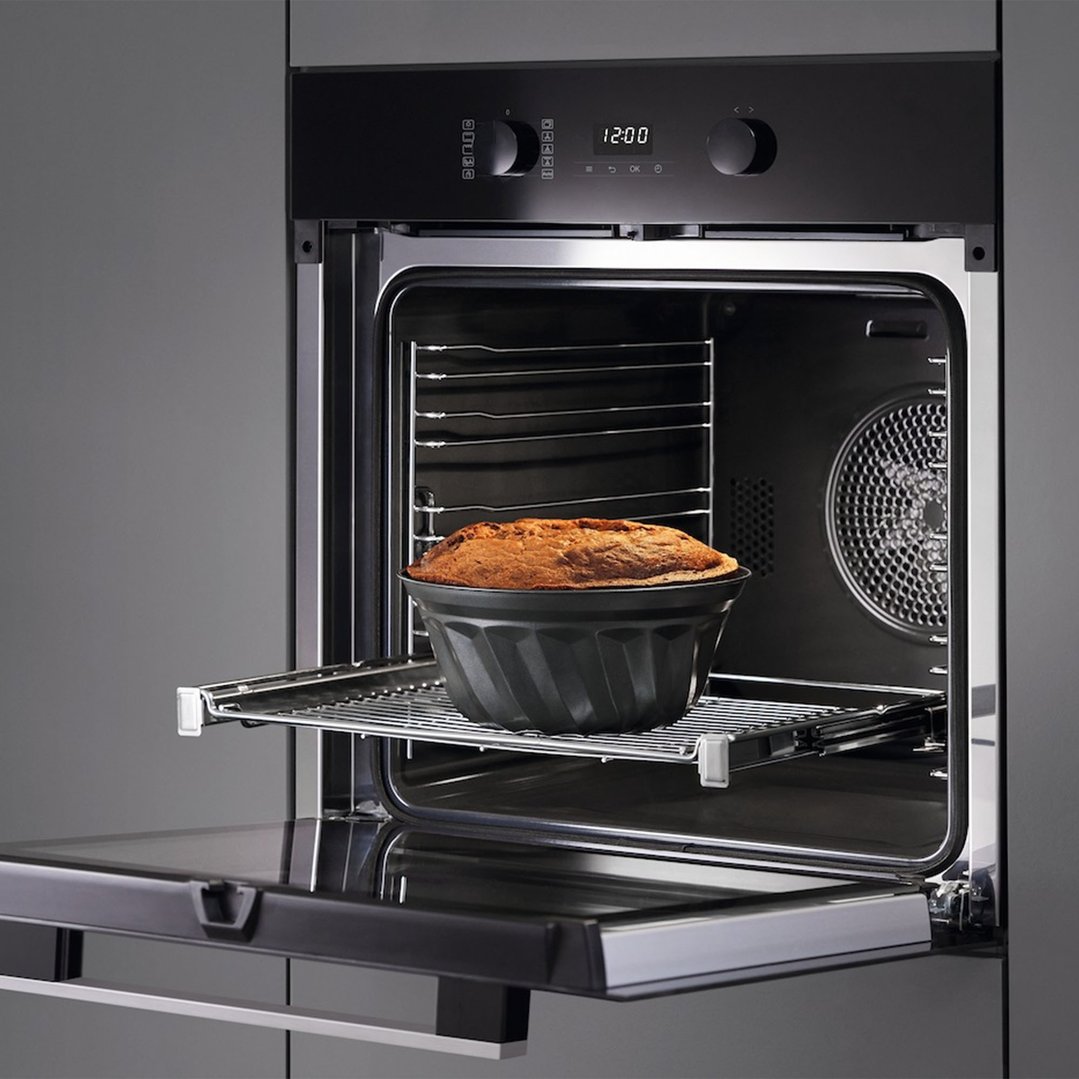 A Miele oven with a cake baking inside, door partially open