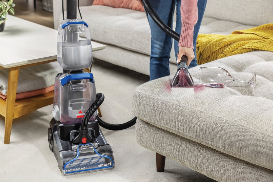 Woman cleaning red wine spill on a sofa with a carpet and upholstery cleaner