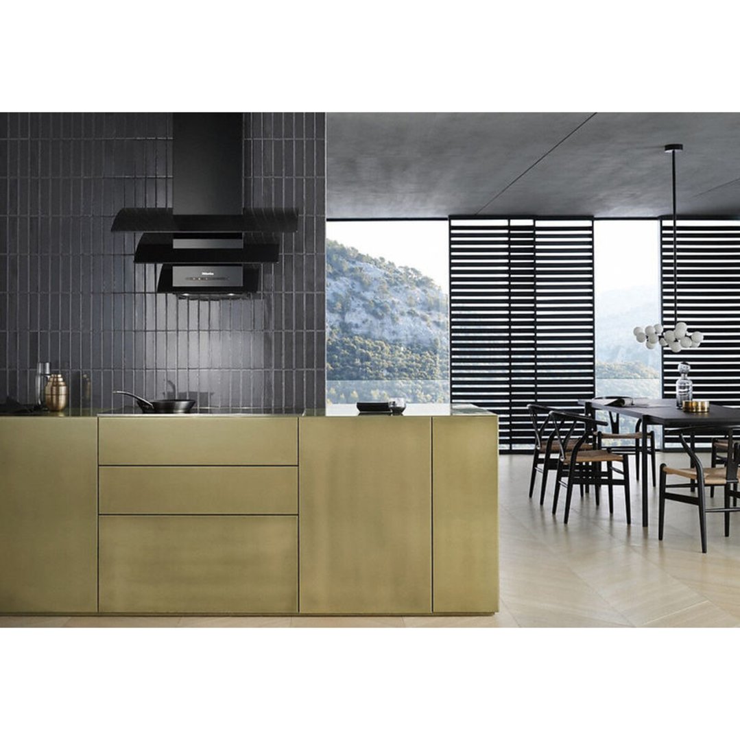 Black wall-mounted rangehood above a gold kitchen island in a modern kitchen