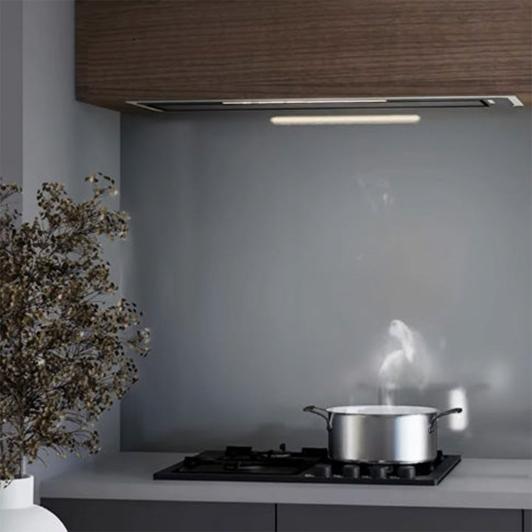 Undermount rangehood installed above a cooktop with a pot steaming in a kitchen
