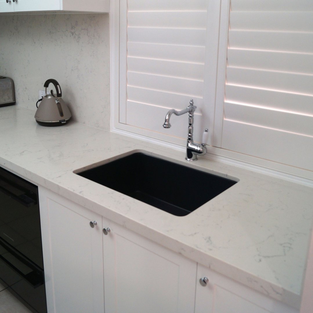 Matte black fireclay butler sink built into a white kitchen countertop