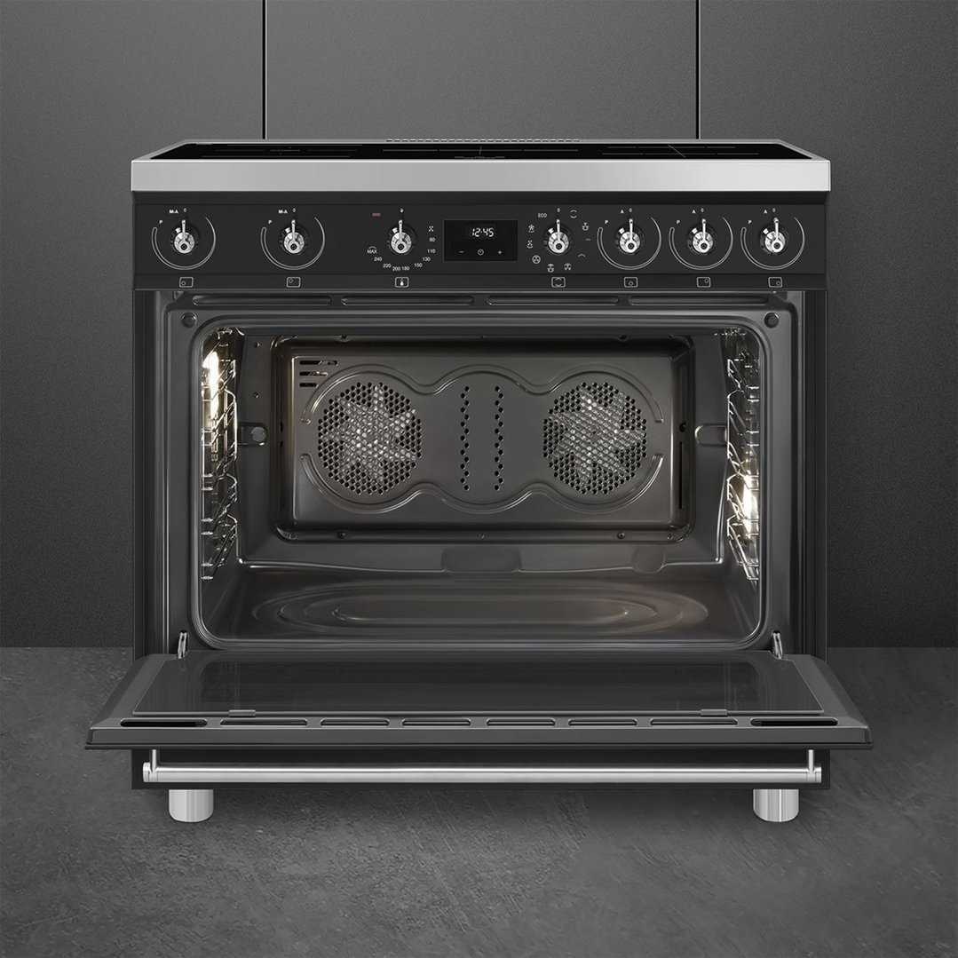 Freestanding oven with door open, showing interior and controls, in a dark kitchen