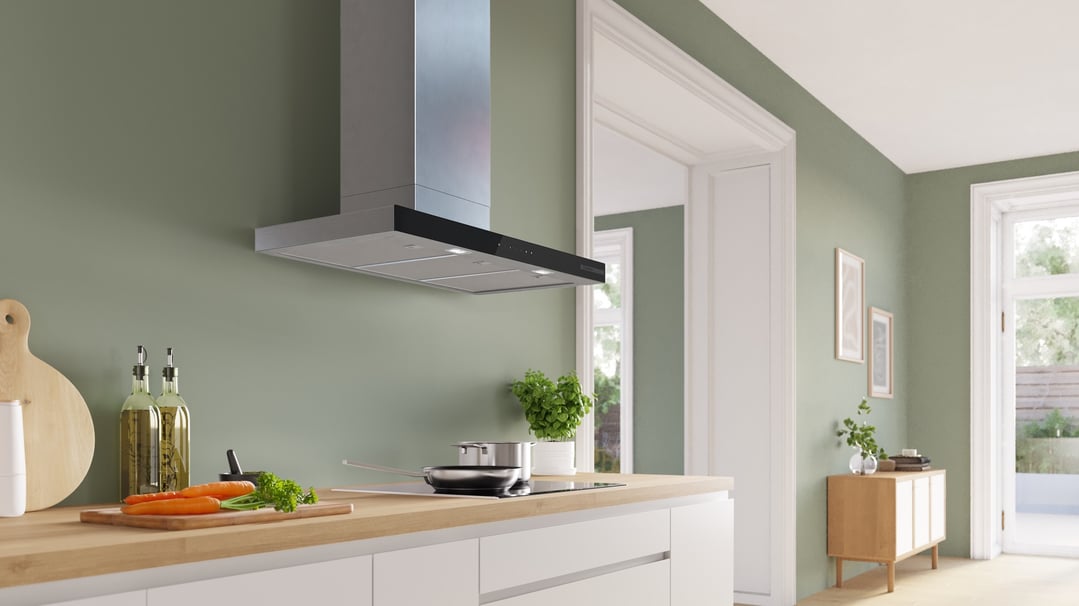 Stainless steel look wall-mounted canopy rangehood above an induction cooktop in a modern kitchen