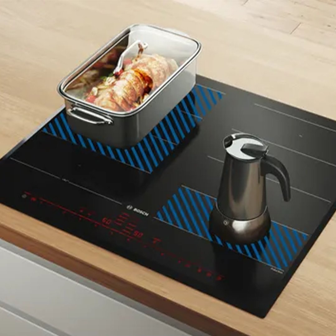 Cooktop with a roasting pan and a coffee maker on a wooden countertop