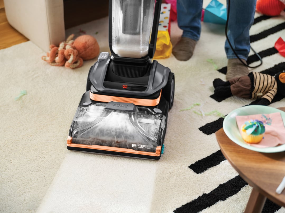 BISSELL vacuum cleaner cleaning a white rug with black stripes in a living room