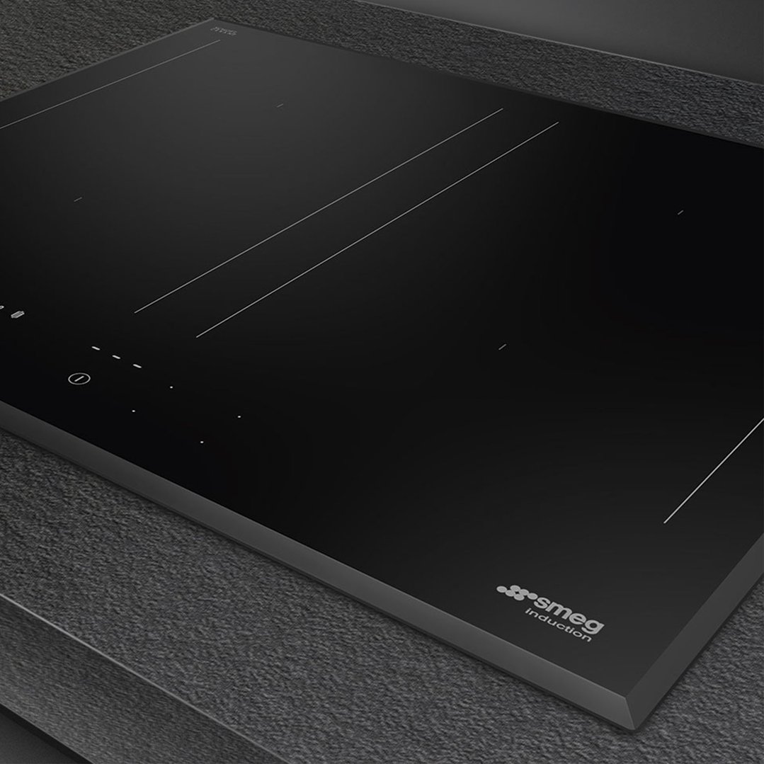 Black induction hob with controls and Smeg logo on a dark countertop