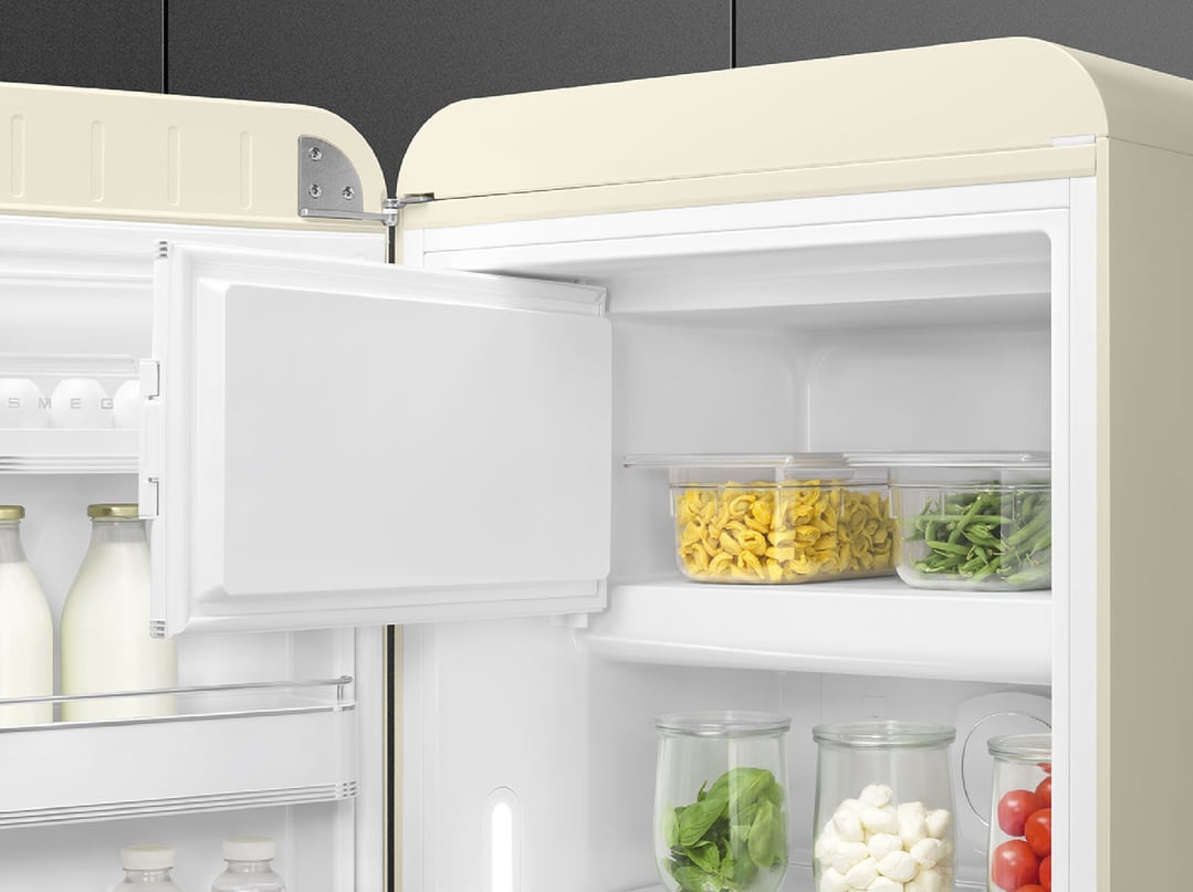 Open cream retro refrigerator filled with food items and bottles