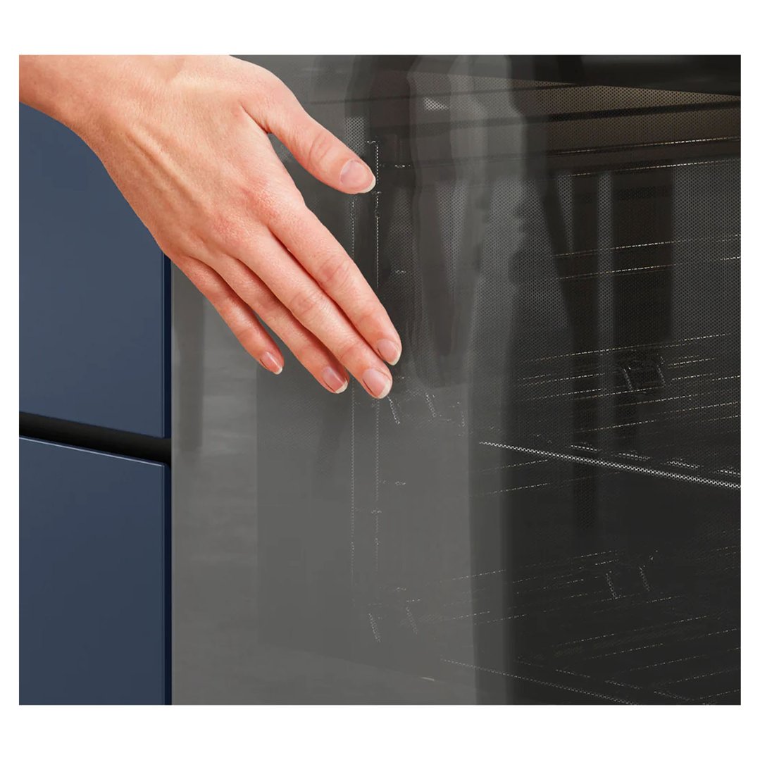 A hand touching the glass door of a dark oven