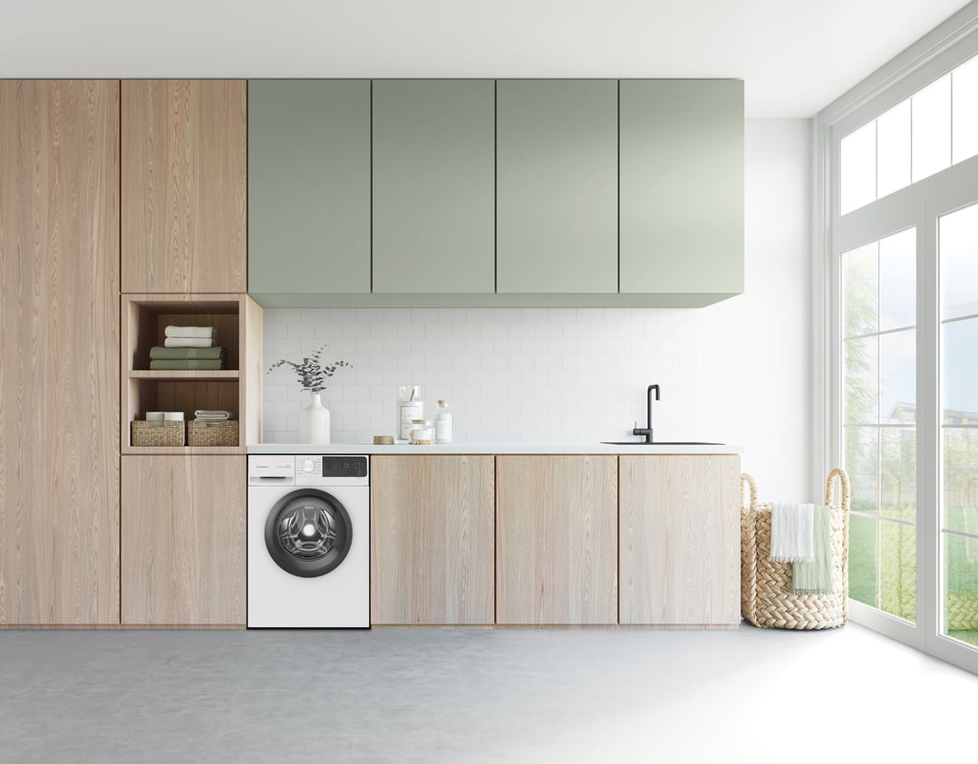 Front load washing machine in a modern laundry room with wooden and green cabinets