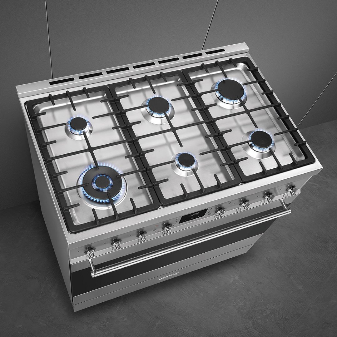 Overhead view of a stainless steel freestanding oven with six gas burners lit