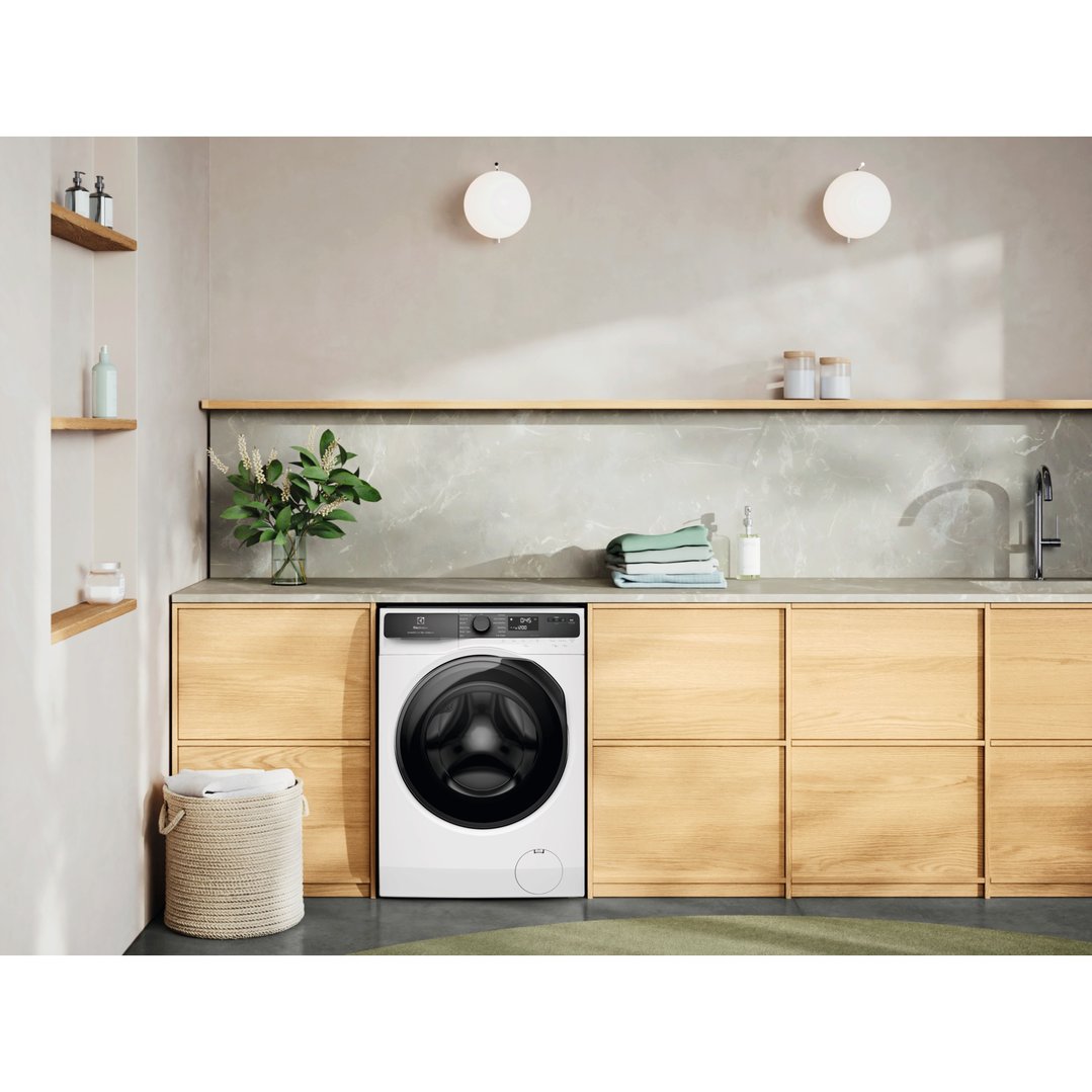 White Electrolux washing machine in a modern laundry room with wooden cabinets