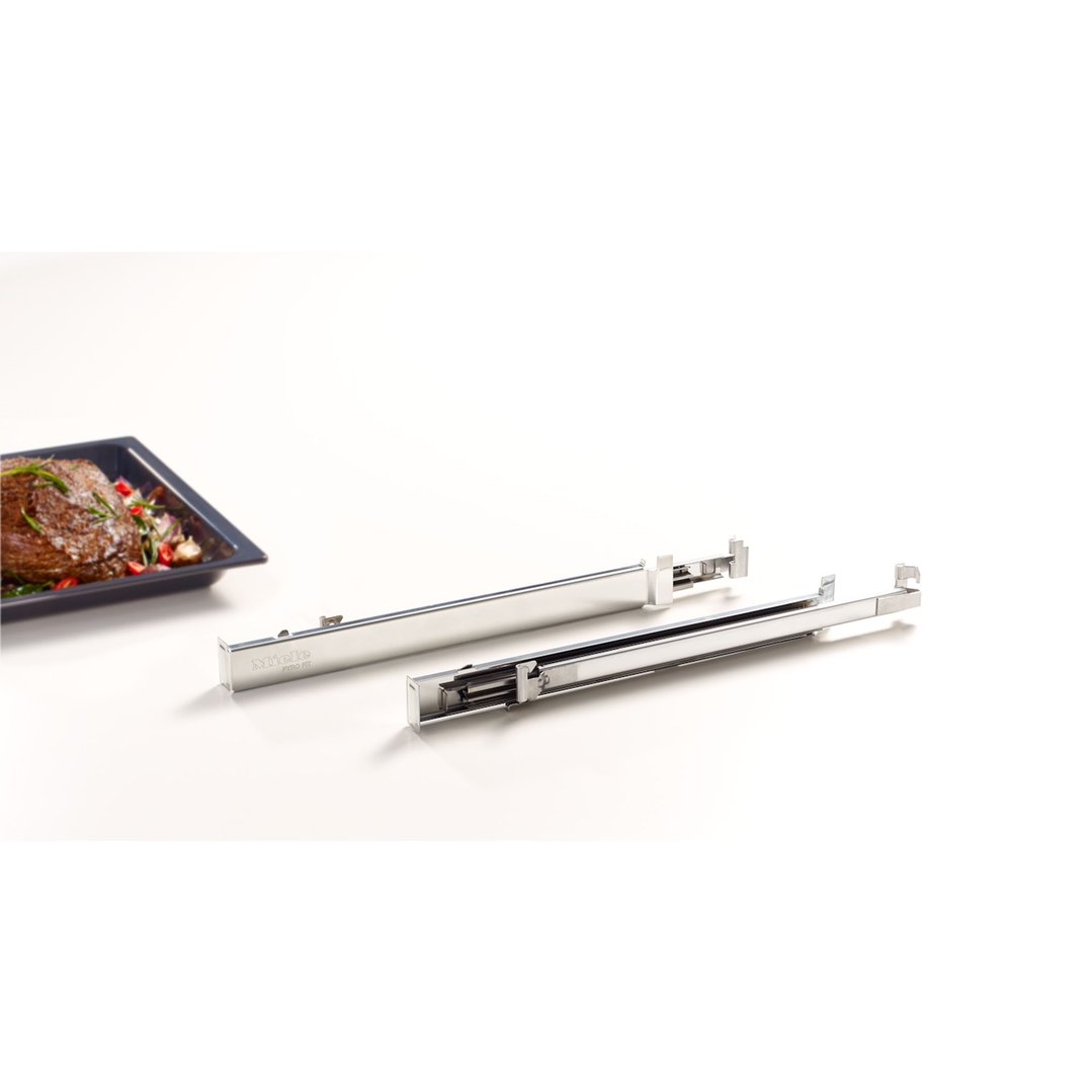Two Miele oven runners next to a roasting pan with meat and vegetables