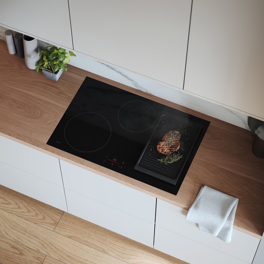 Induction cooktop with a steak on a grill pan in a modern kitchen setting