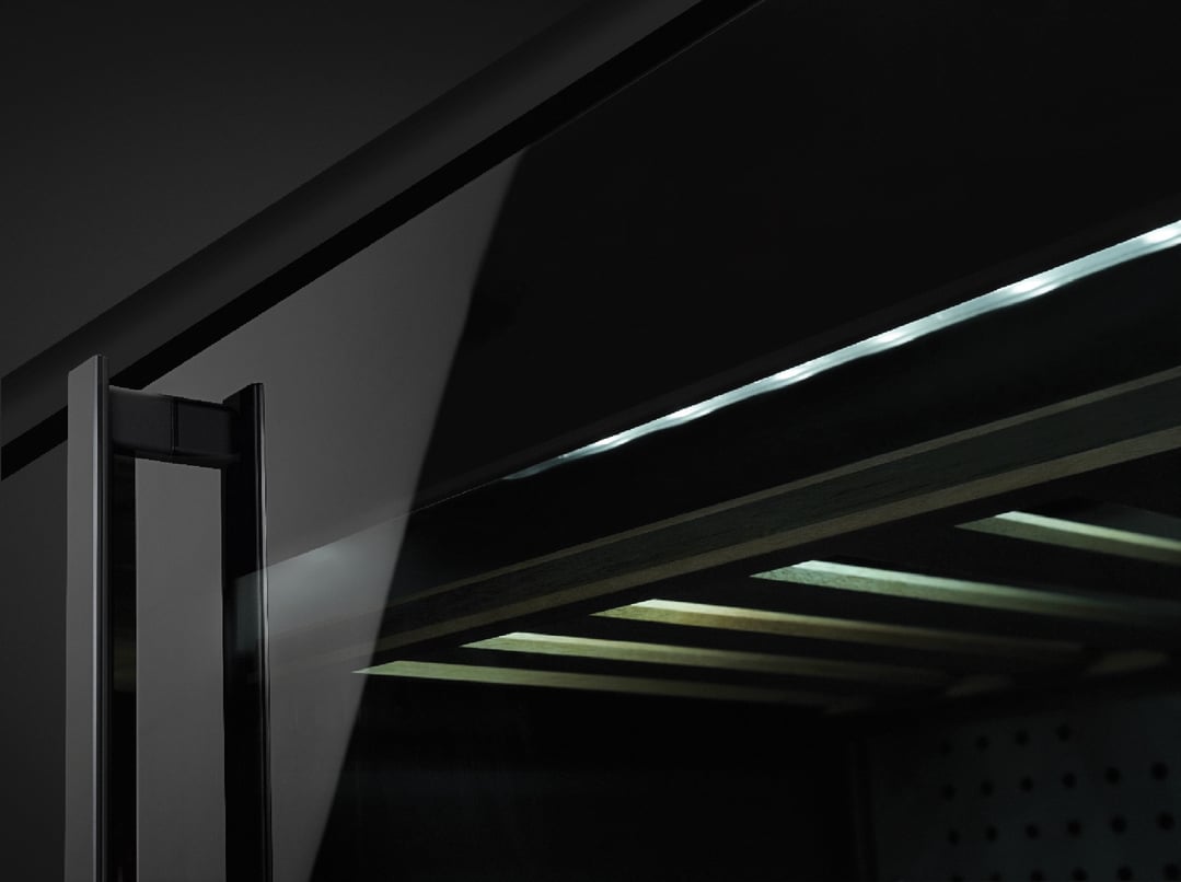 Close up of a wine cooler door with interior lighting and wooden shelves