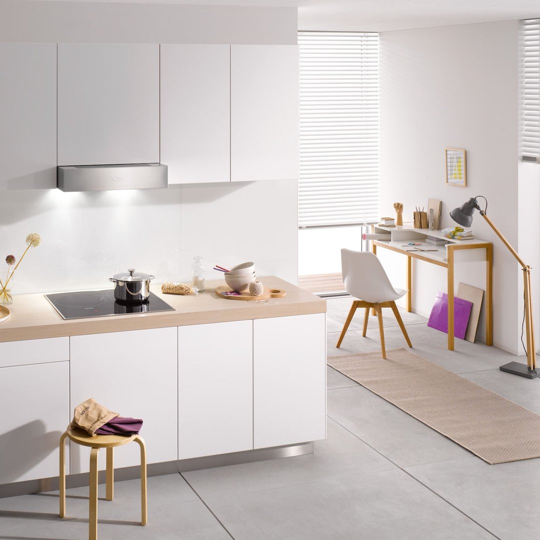 Rangehood installed above an induction cooktop in a modern kitchen and office space