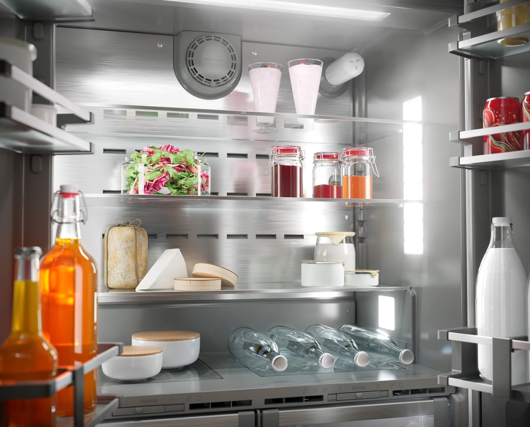 Open integrated fridge with various food items and drinks on shelves