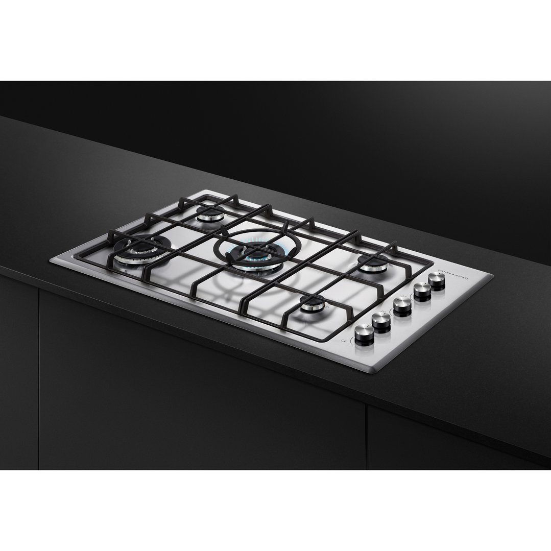 Stainless steel gas cooktop with five burners on a black countertop
