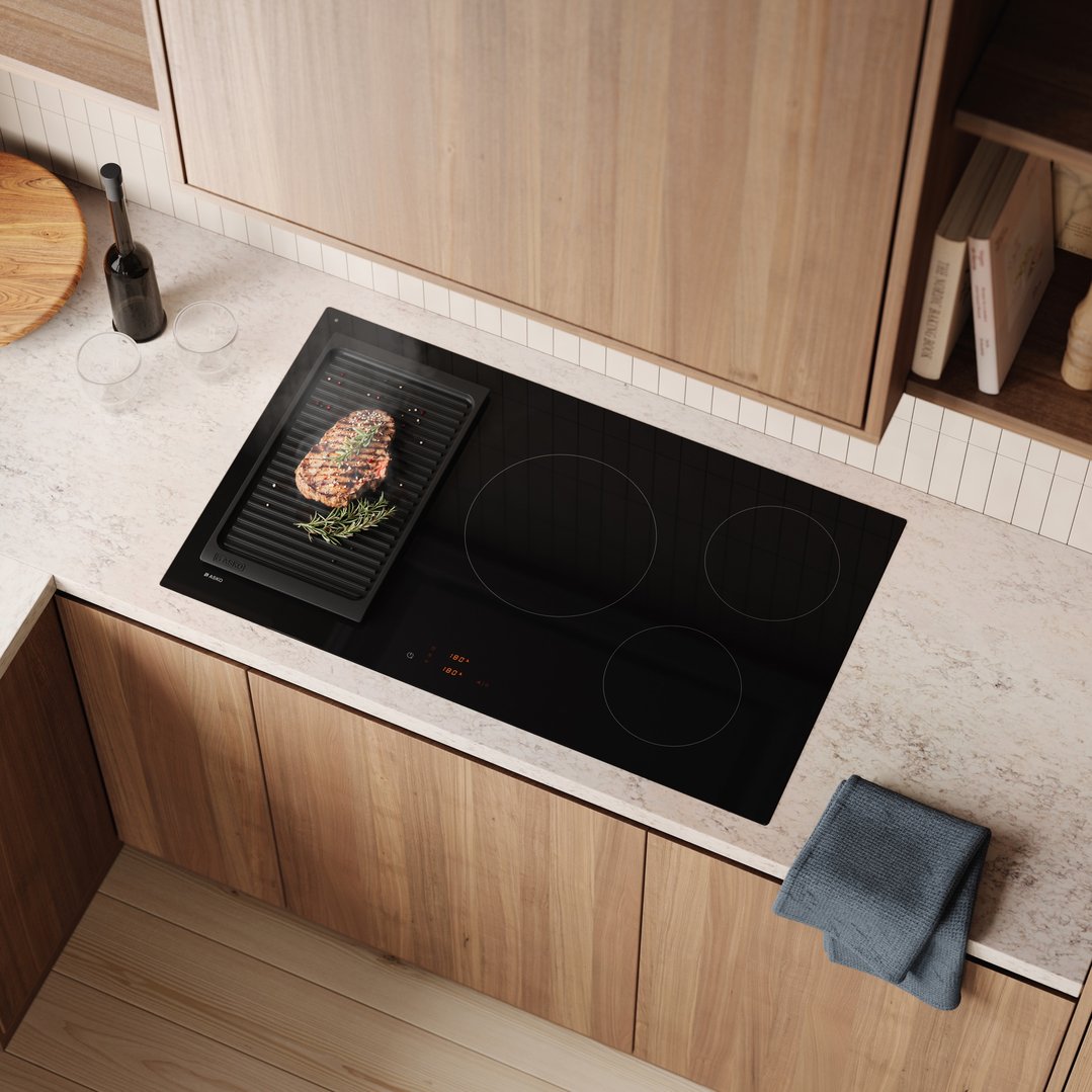 Overhead view of a black induction cooktop with a steak grilling on it