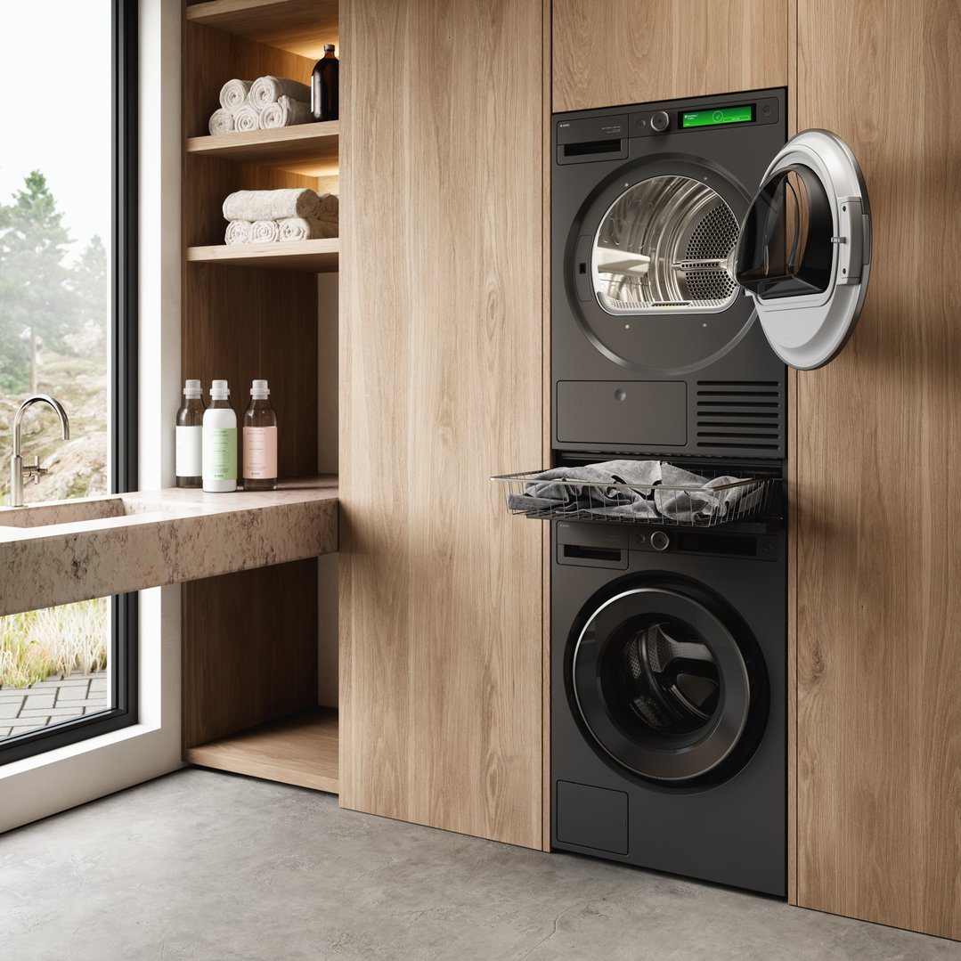 A laundry room with a stacked washer and dryer and a pull-out basket