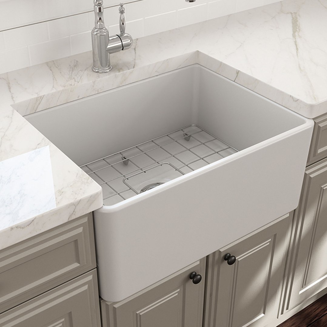 White fireclay butler sink with a metal grid in a kitchen setting