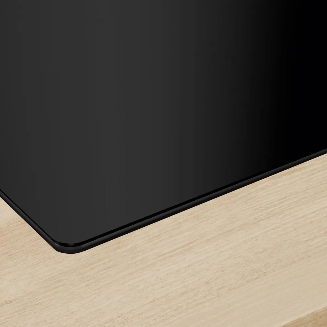 Close-up of a black cooktop with integrated ventilation on a light wooden countertop