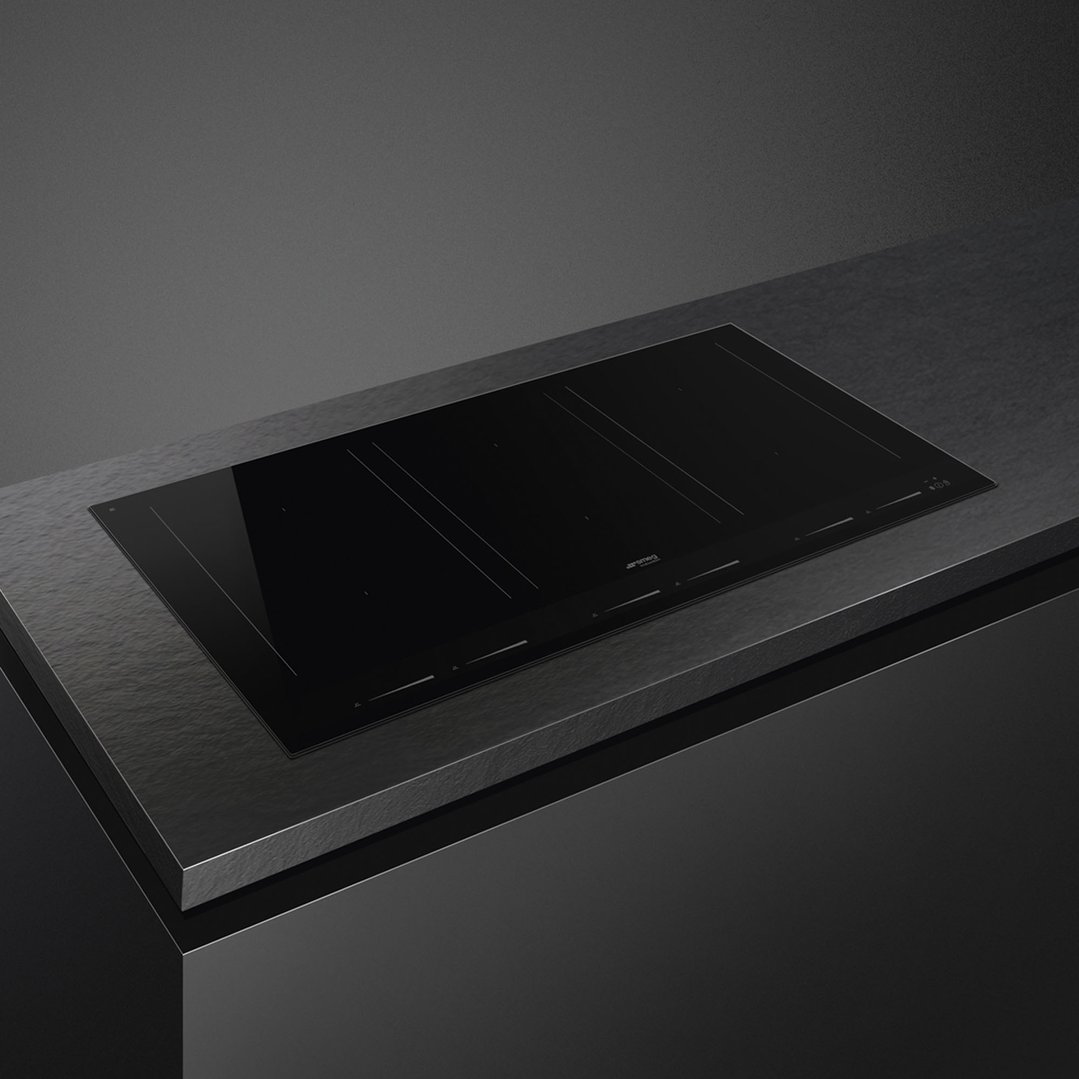 Black induction cooktop built into a dark countertop in a modern kitchen