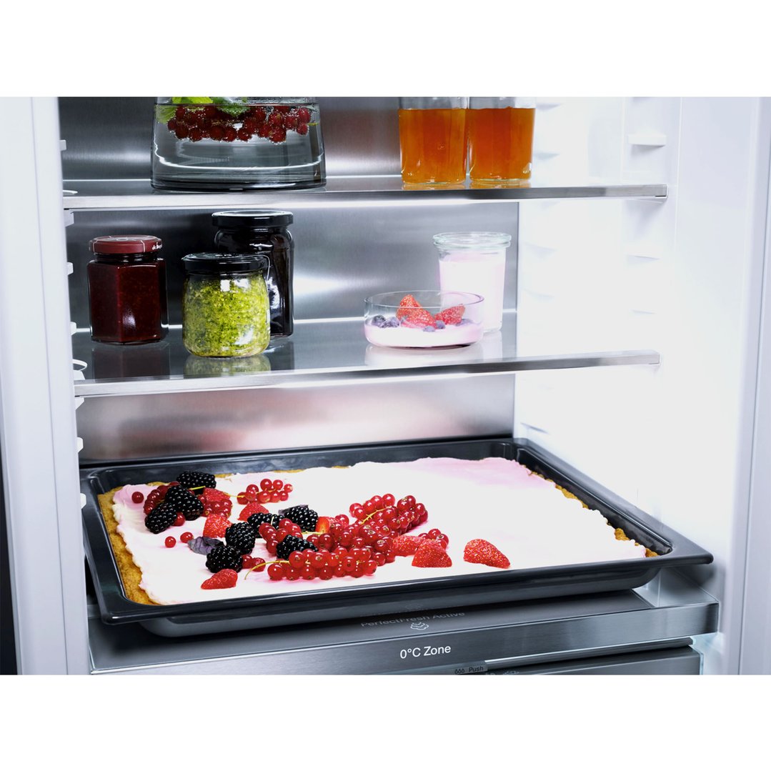 Open fridge interior with food items on shelves and a berry tart on a tray