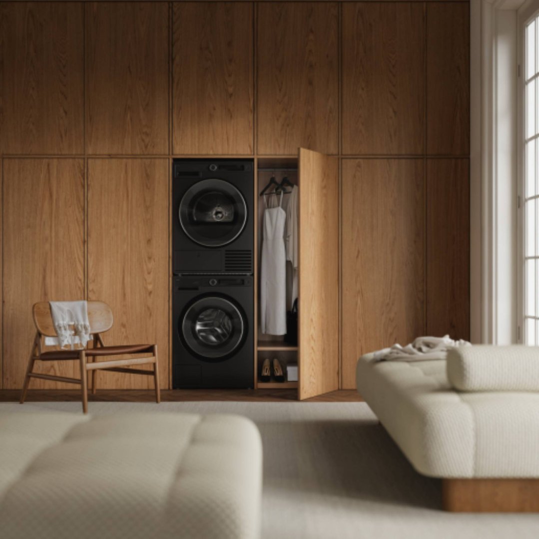 Black dryer and washing machine built into a wooden cabinet in a room