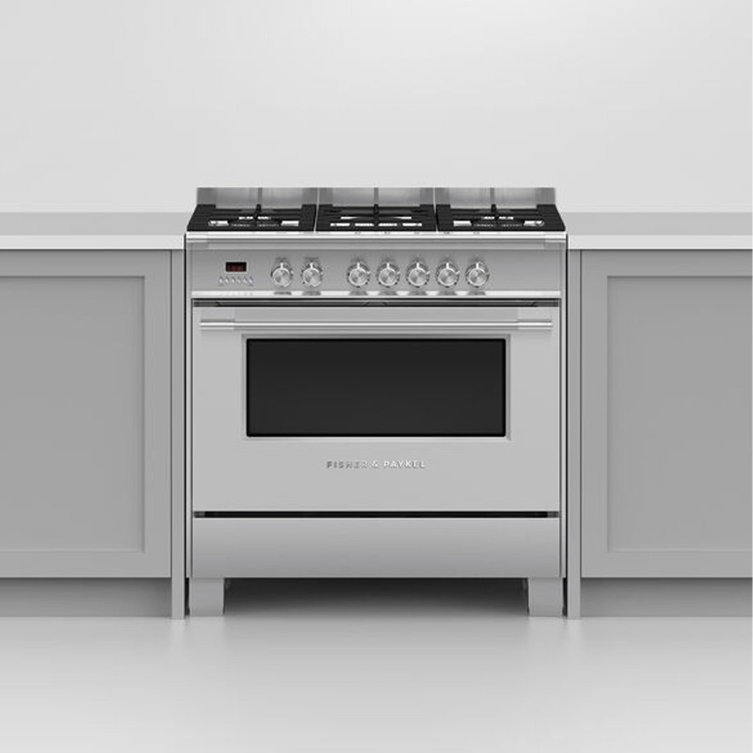 A stainless steel dual fuel cooker installed between light grey kitchen cabinets