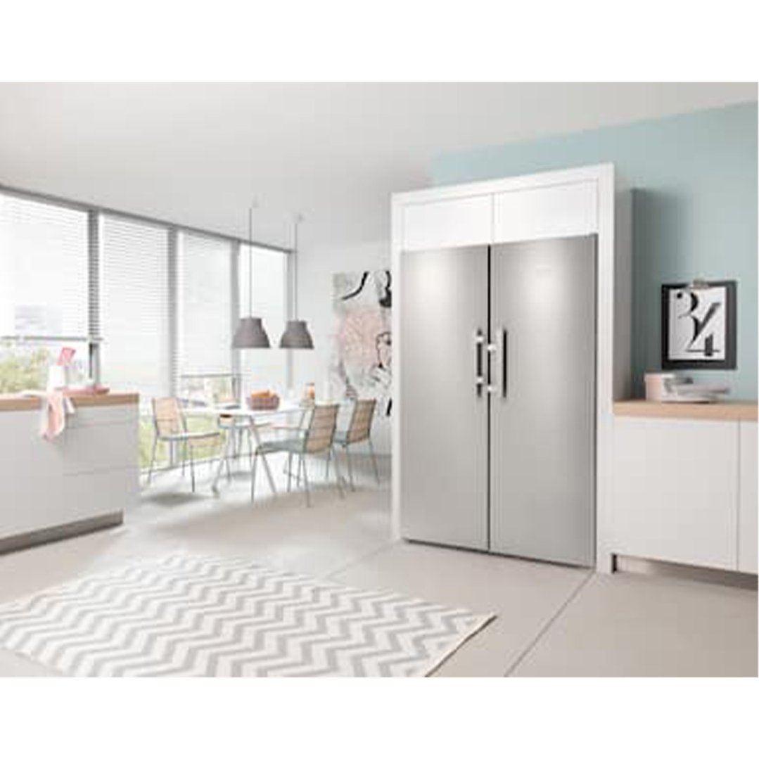 Stainless steel side-by-side refrigerator in a modern kitchen with dining area