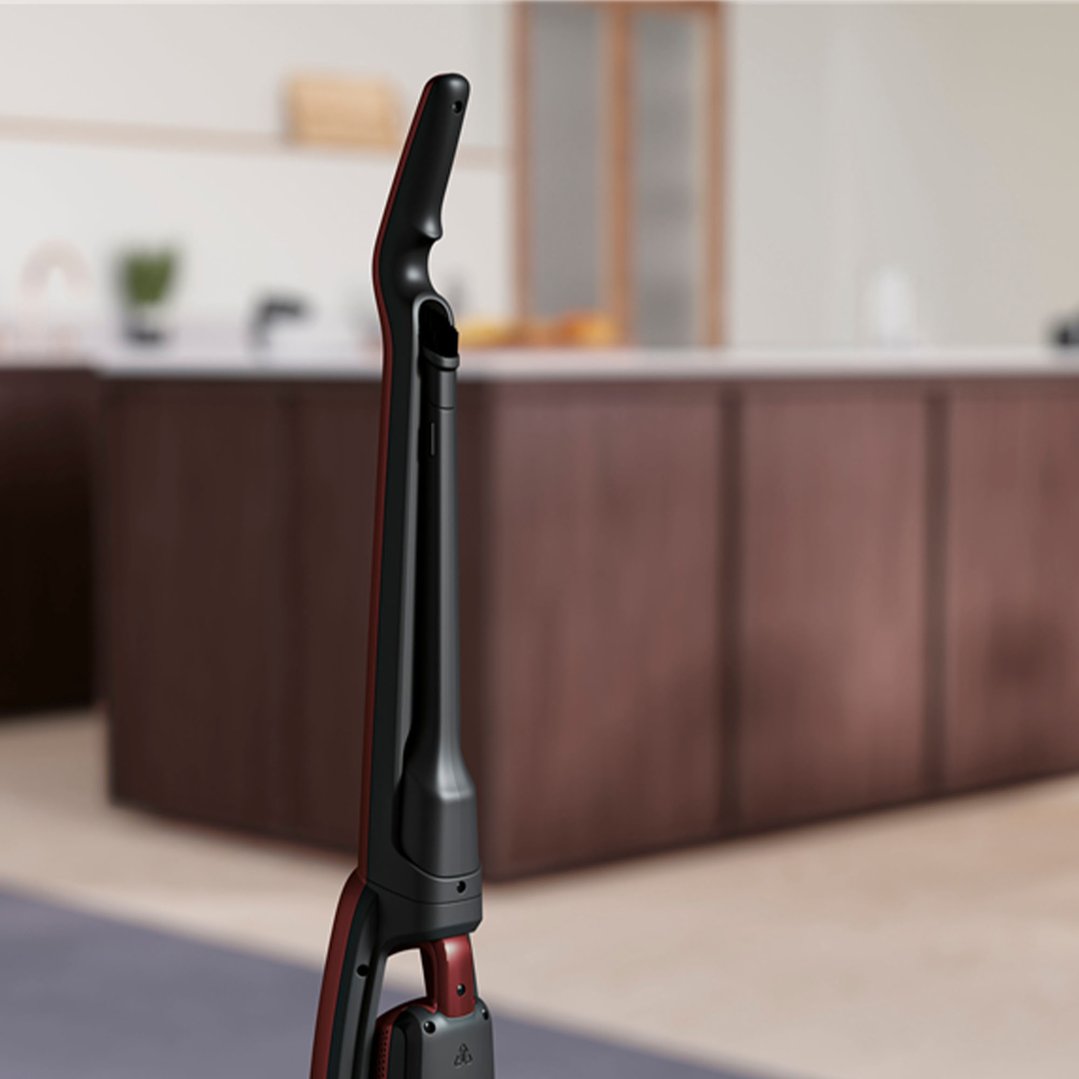 A red and black cordless vacuum cleaner standing in a modern kitchen