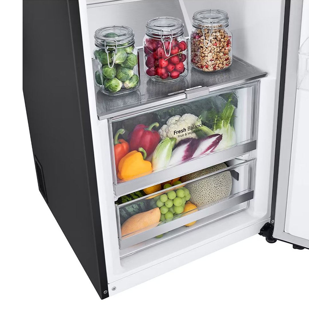 Open single door fridge interior with fresh produce in drawers and jars