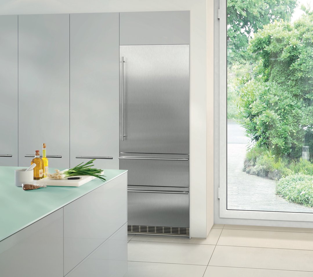 Integrated bottom mount fridge in a modern kitchen with a green countertop and window view