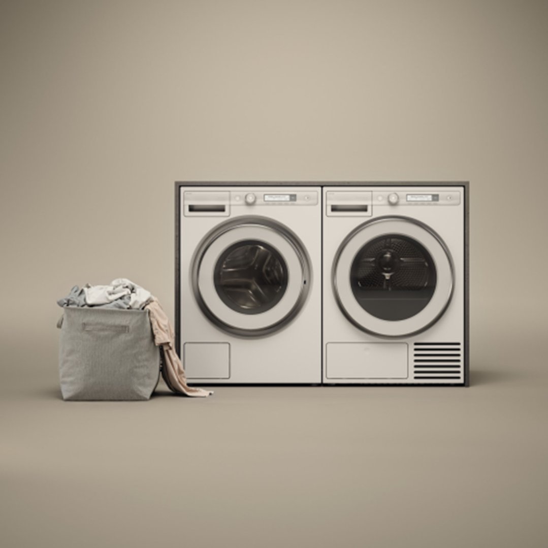 Two white dryers side-by-side with a laundry basket full of clothes