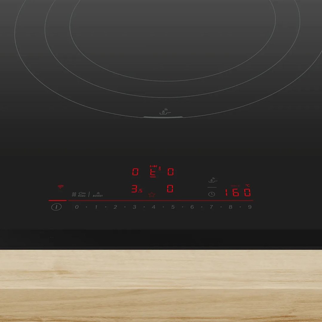 Black induction cooktop with illuminated controls on a light wooden countertop