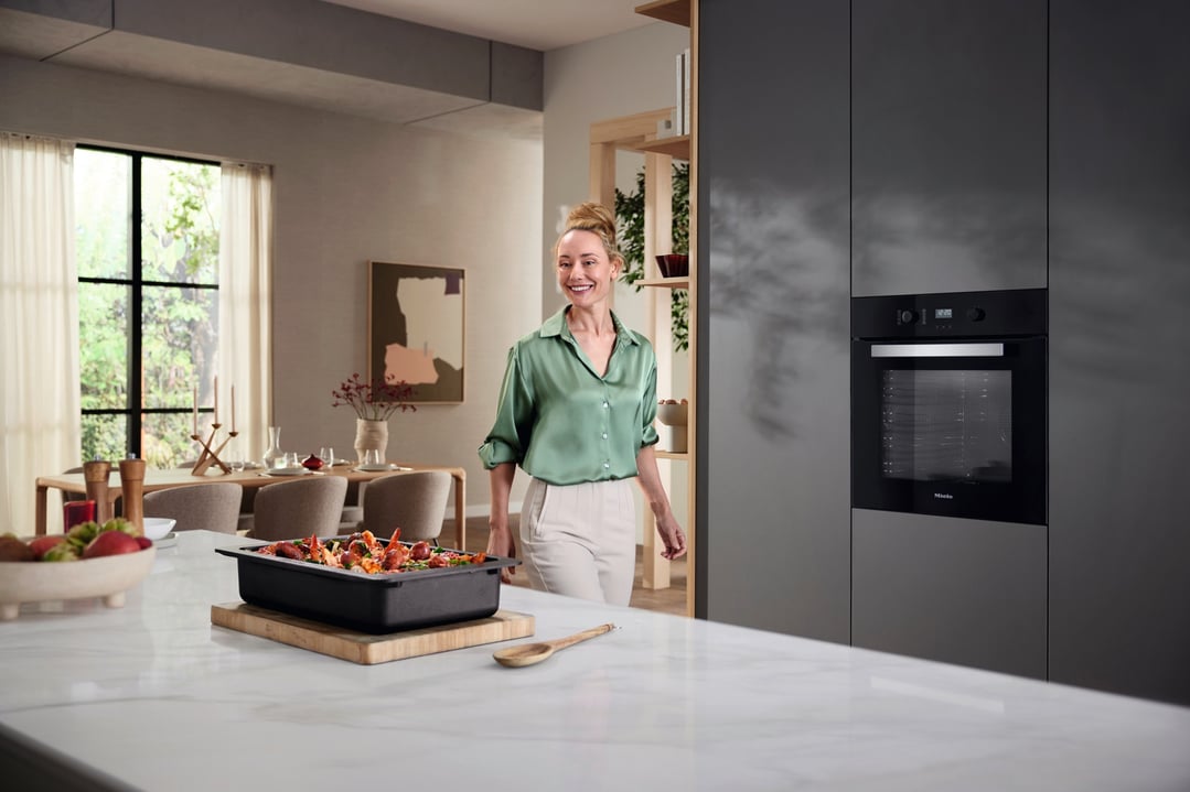 Woman smiling in a modern kitchen with an oven and food on the counter