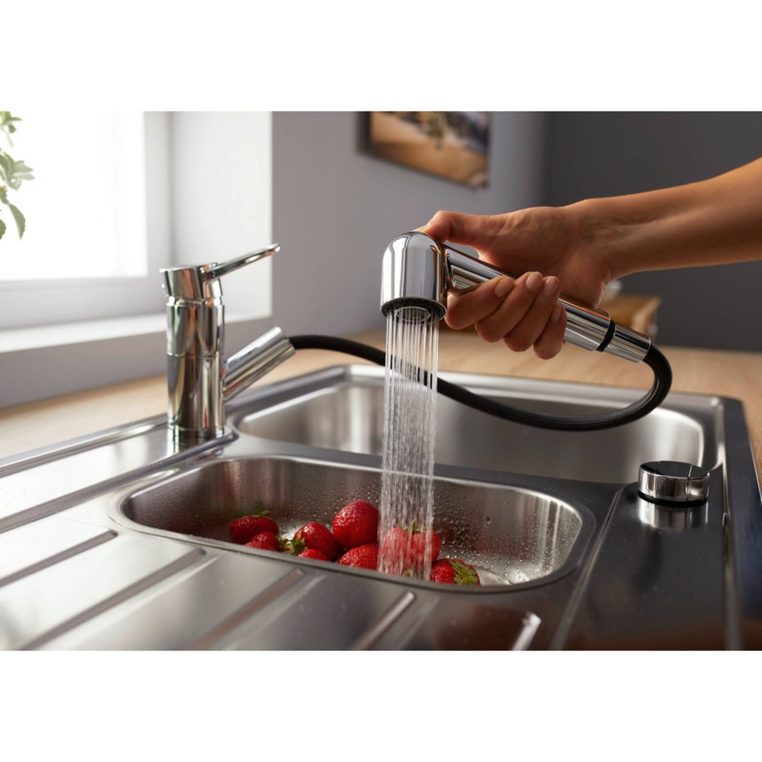 Hand holding a BLANCOWEGA-S II tap, rinsing strawberries in a sink