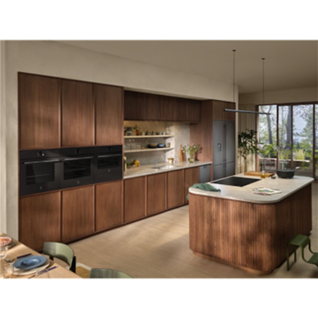 Three built-in ovens in a modern kitchen with wooden cabinets and island