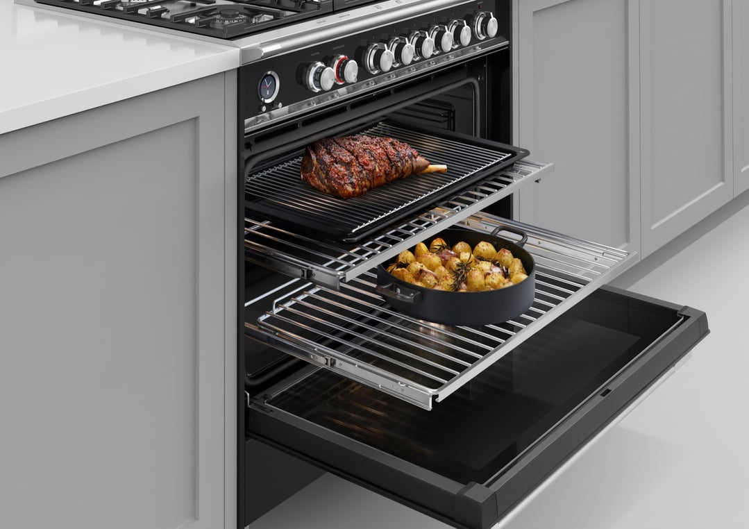 Freestanding oven with a roast and potatoes cooking inside, in a kitchen
