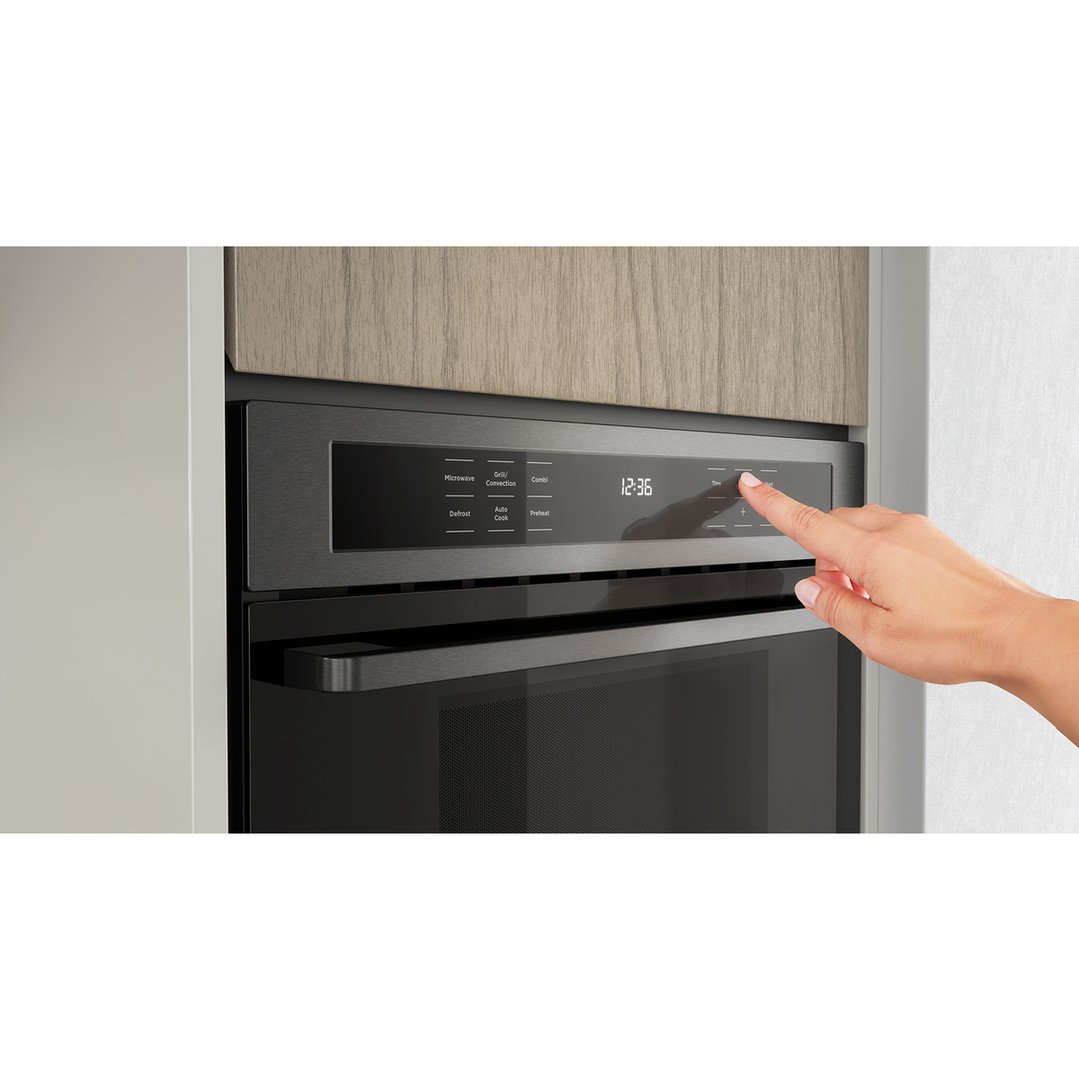 Hand pressing the control panel of a built-in combination microwave