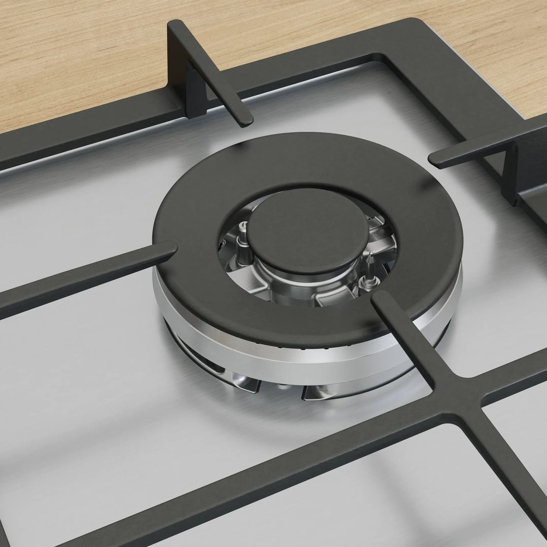 Close-up of a gas cooktop burner and grates on a wooden countertop