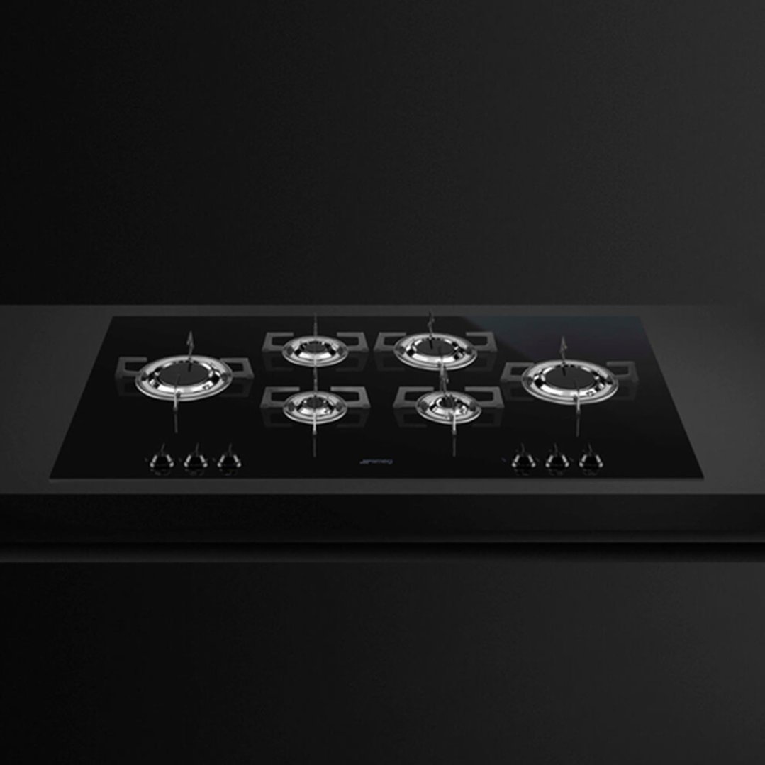 Black gas cooktop with six burners on a dark countertop