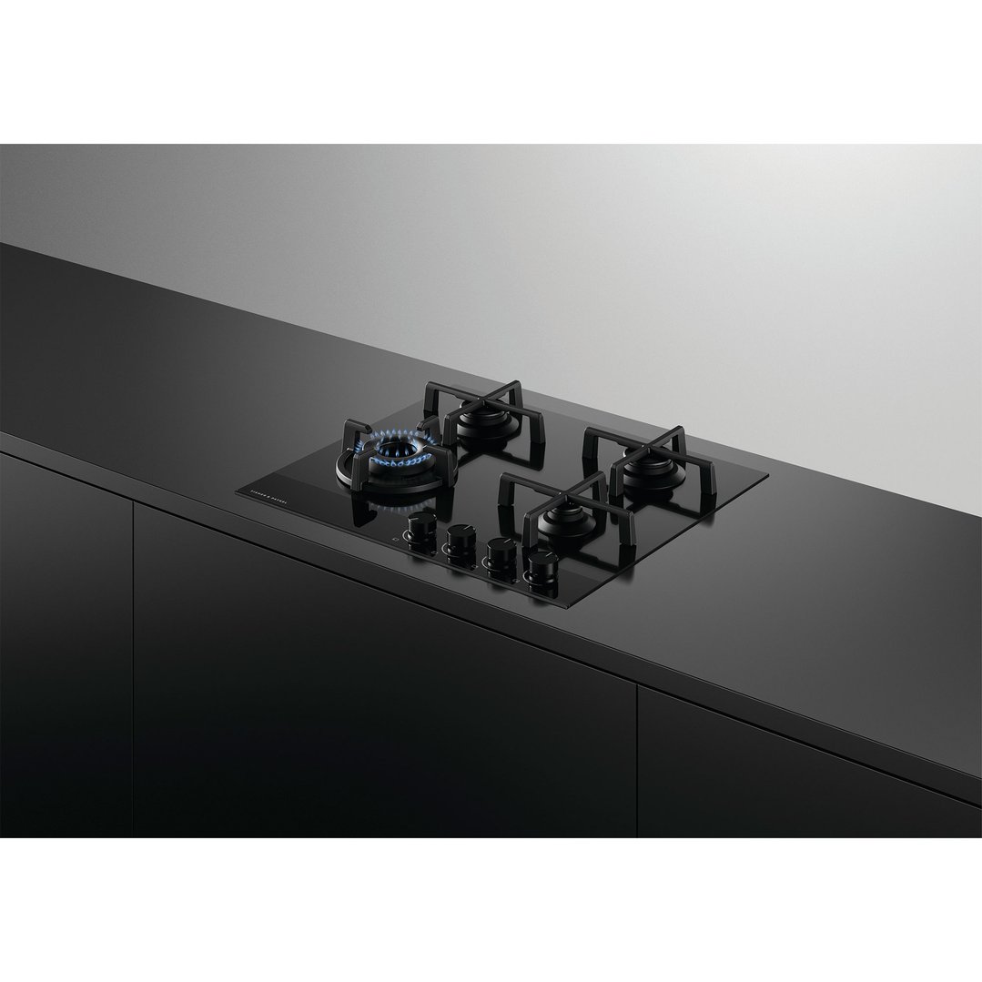 Black gas on glass cooktop with one burner lit in a modern kitchen