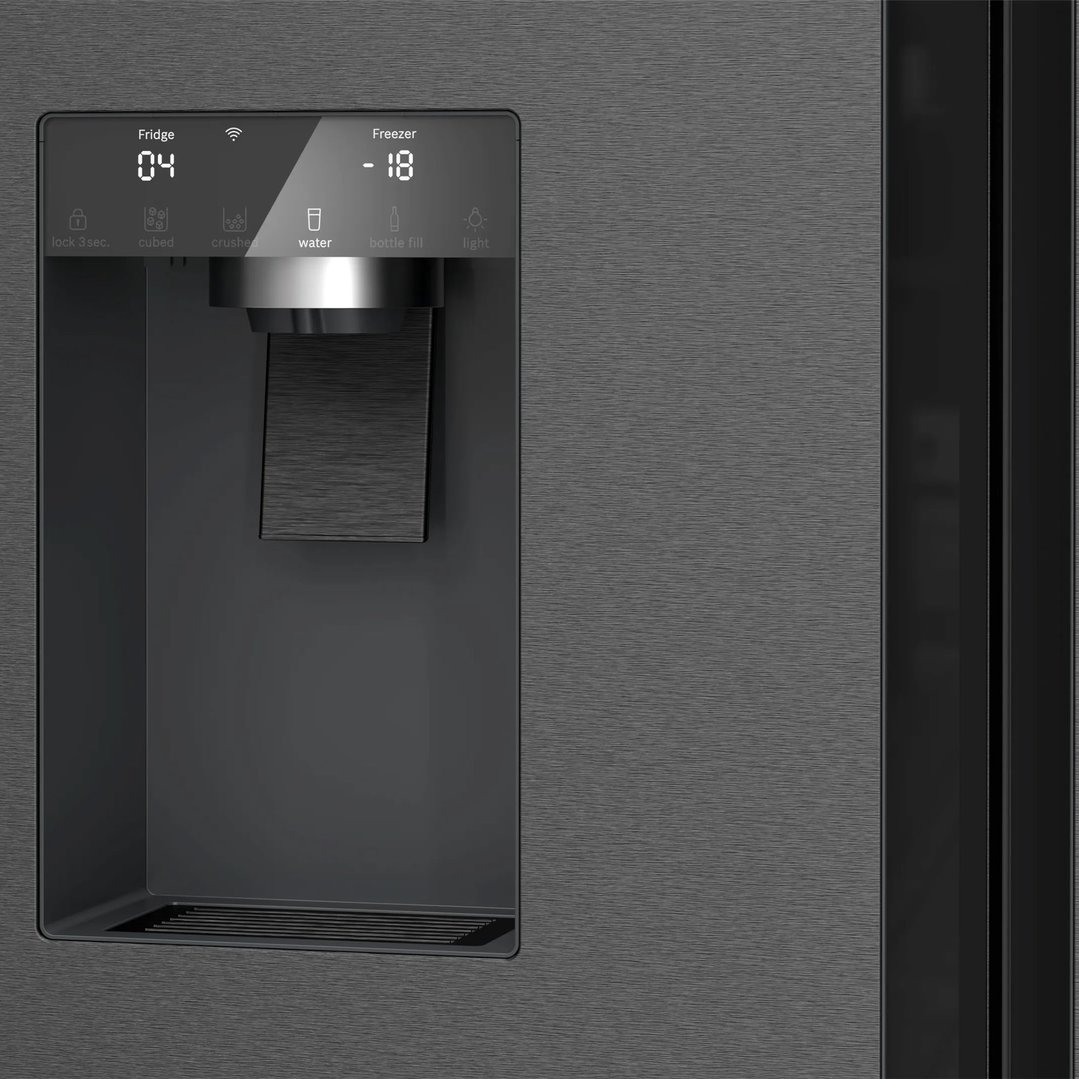 Close-up of the water and ice dispenser on a brushed black steel fridge freezer