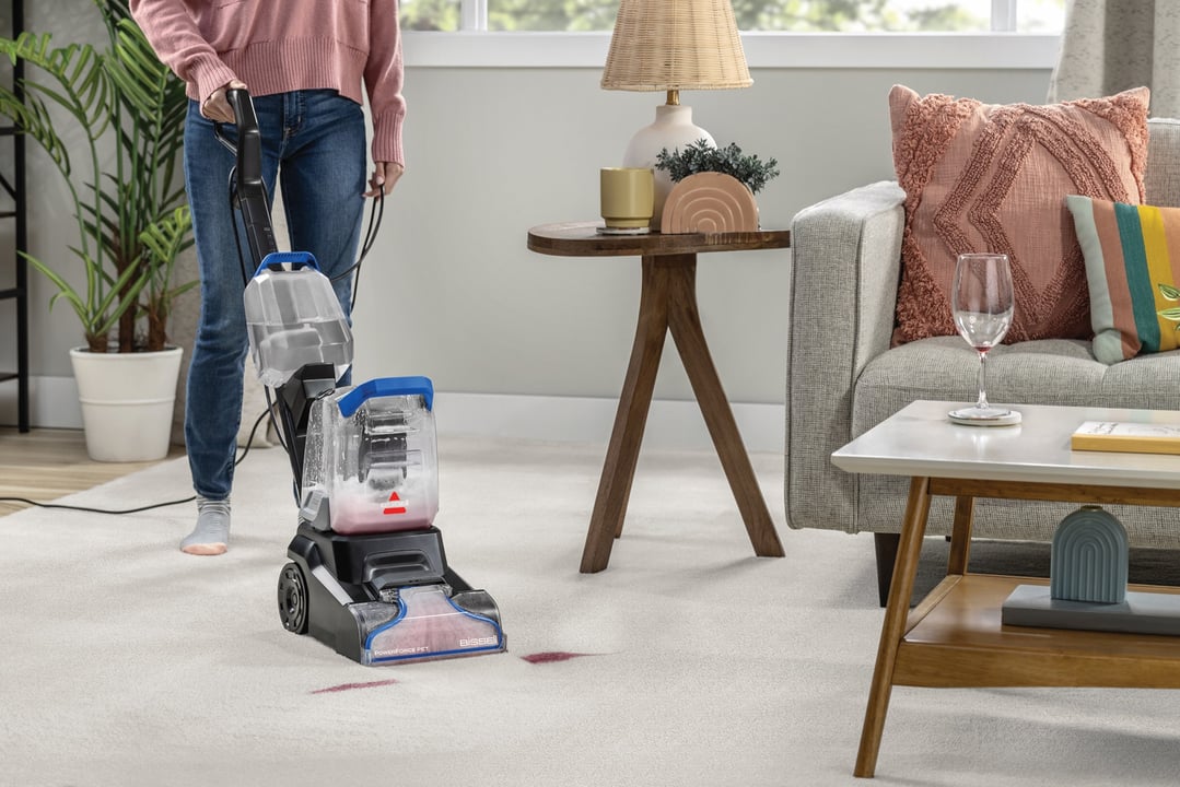 Woman using a BISSELL PowerForce Pet upright carpet cleaner on a white carpet