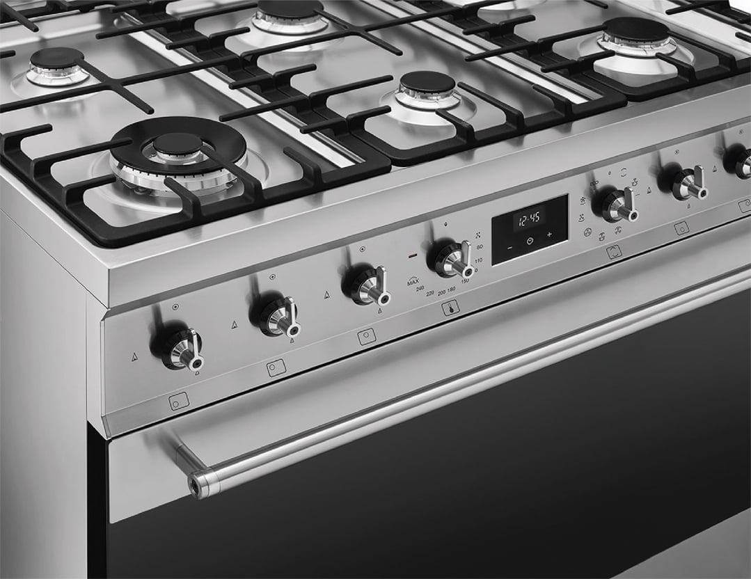 Close-up of a stainless steel freestanding cooker with gas burners and control panel