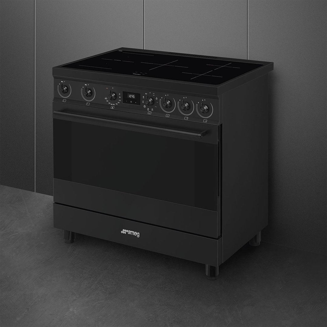 Matte black freestanding cooker with induction hob in a dark kitchen setting